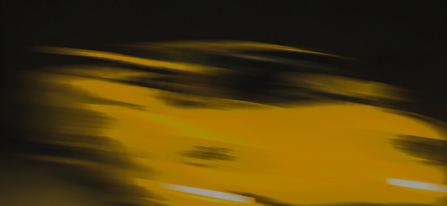 Yellow sports car panning past a snow-capped mountain
